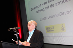 Jeanne Devos, met achtergrond titel van de publiekslezing met Amnesty International-logo